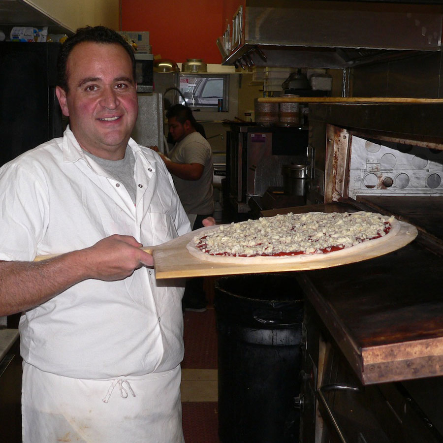 Vinny Savinelli loads a pizza into the oven.